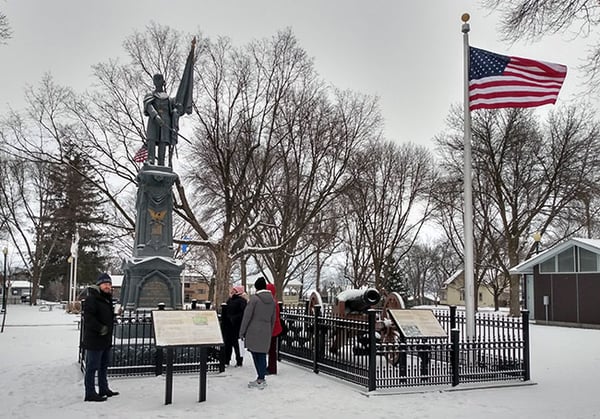 Three people standing around two US Civil War monuments consist of a Union soldier statue on a pedestal and a canon.jpg