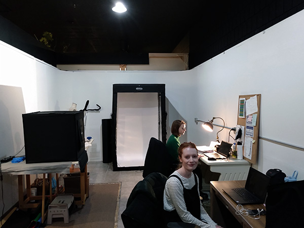 Two Project staff sitting at computers in white room with lightboxes and scanners