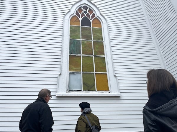 Three people looking up at a Life Tabernacle stained glass window