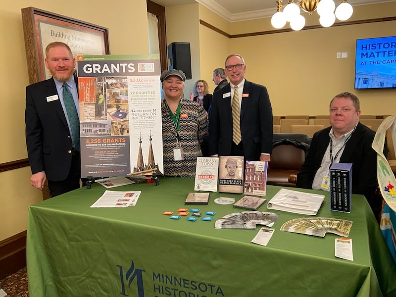 Table set up at the State Capitol with Grants information panel on table. For people standing behind table