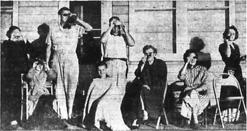 Black and white photo of eight people in front of house watching the Eclipse