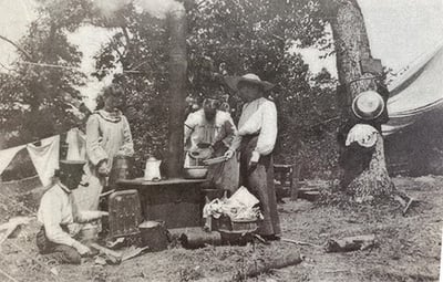 Victorian era photos of three women and a man standing outside camping around a iron stove