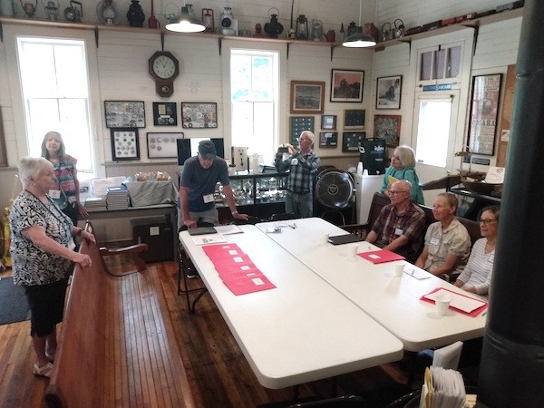 People standing and sitting around a large table in a depot museum.