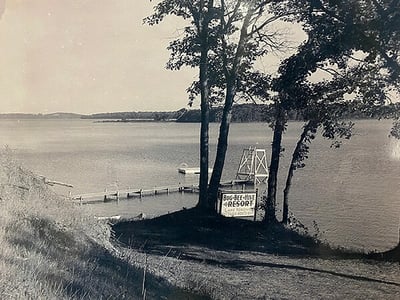 Lake shore with dock and diving platform with  sign saying Bug BeeHive Resort