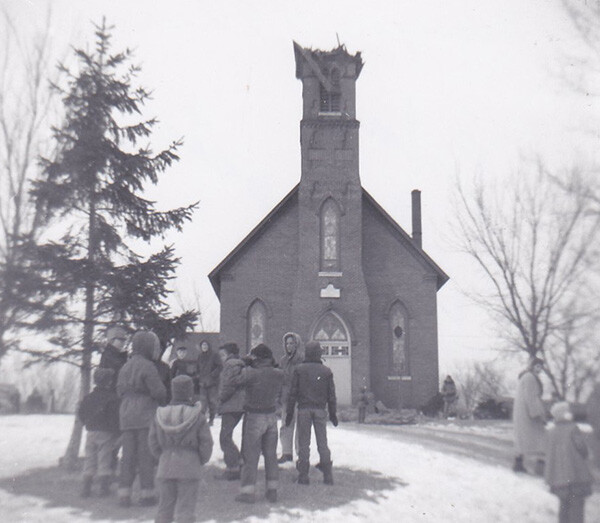 Demolition of St. Johns Chapel in 1956 with a group of people standing outside in winter