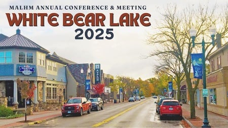 Photo of a quant main street of business. On the photo is says MALHM Annual Conference and Meeting White Bear Lake 2025