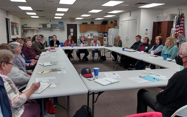 A group of 18+ people meeting round set up tables