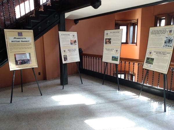 Four poster panels on easels, in the background is a stairwell