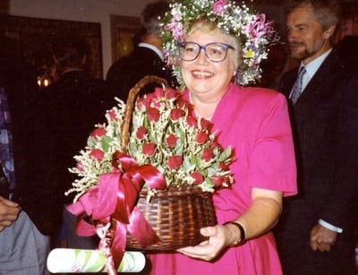 Margaretha Hedblom carrying a basket of red roses. She is wearing a garland of her head