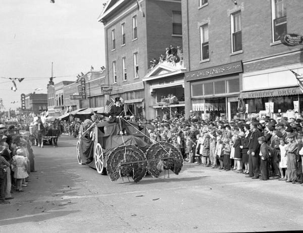 Parade with float of fake turkeys pulling float