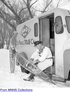 Milk man sitting on truck putting on snow shoes