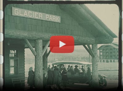 Film still of Glacer Park Train Station with people crowding on to a bus. ca.1920