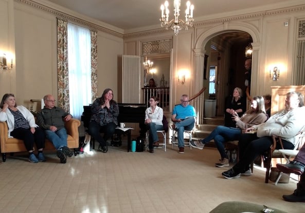 People sitting in chairs in a semi-circle in a very posh livingroom