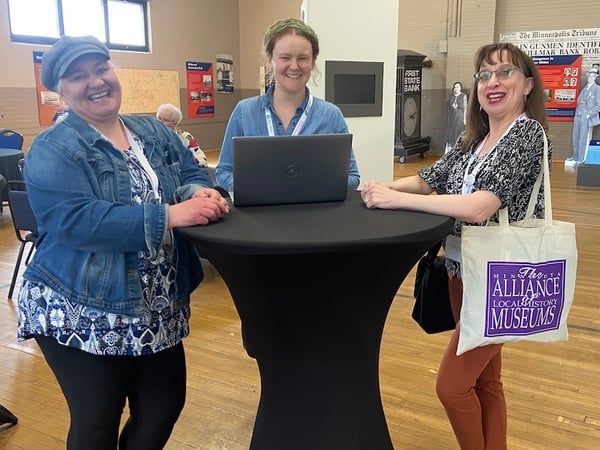 Three women standing around tall tall smiling and laughing