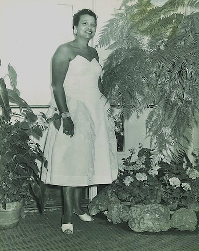 Anna Belle Rideaux standing for portrat in dress surrounded by plants