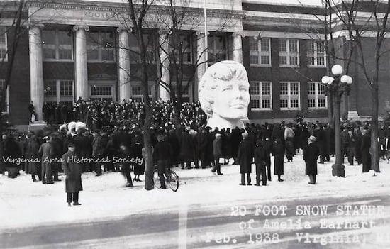 Black and white postcard photo of a 20 foot snow head bust statue of Amalia Earhart