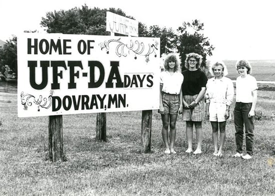 Black and white photo--Sign-Home of UFF-DA Days Dovray, MN-Four young women are standing to he right of it