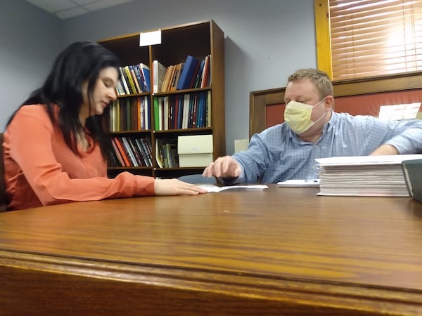 two people at wooden table looking over documents