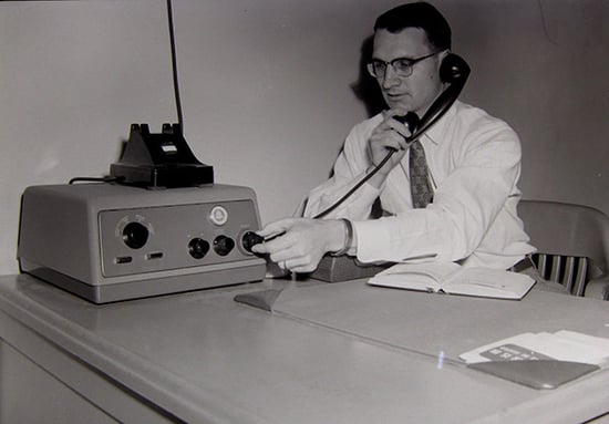 Man at table working an anwering machine in the 1940s