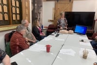 People around table with AED device and practice dummy in center
