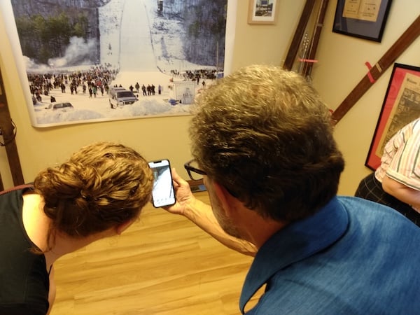 Examining exhibit and a video on mobile phone at the American Ski Jumping Museum and Hall of Fame