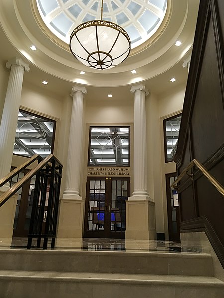 Rotunda with Pillars and hanging light fixture. At the library entrance above the french doors is a sign saying-COL JAMES B LADD MUSEUM CHARLES W NELSON LIBRARY