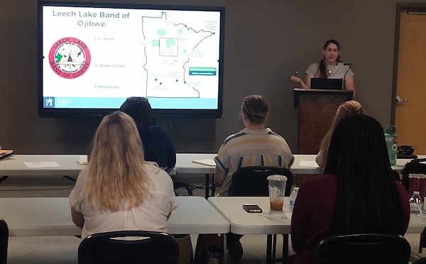Native Nations and Local History Organizations Workshop Presenter at front of class. In foreground are attendees sitting at tables with backs to camera
