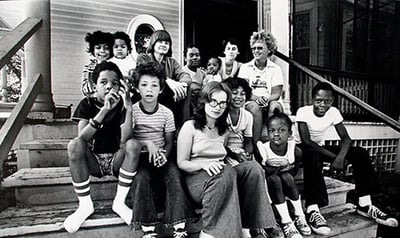 A group of children and adults sitting on front steps of house
