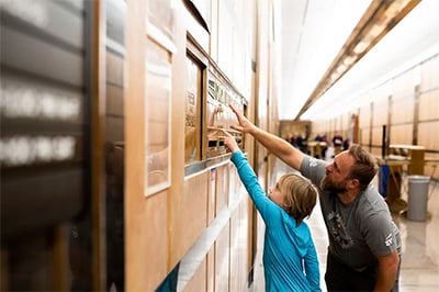 Father and son pointing at the mail deposit chute at the Minneapolis Post Office during Doors Open Minneapolis