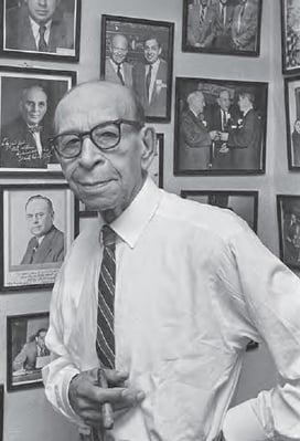 BIlly Williams standing with cigar in front of framed photos