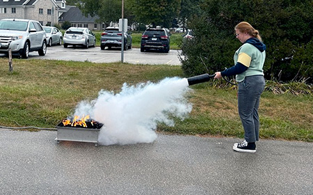 Woman putting out fire in a fire pit with fire extinguisher