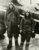Black and white photograph of Charles and Anne Lindbergh in flight suits next to Lockheed Sirius during their flight across the Northern Pacific, c.1931.