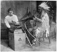 Black and white photograph of Frances Densmore with Mountain Chief who is interpreting a recording.