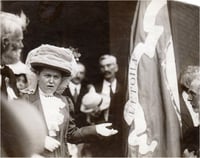 Black and white photograph of Mary Mehegan Hill speaking at a St. Paul event marking the fiftieth anniversary of the First Minnesota Volunteer Infantry Regiment’s departure for Civil War duty, 1911.. Hill presented a duplicate of an old Regimental flag to the group.