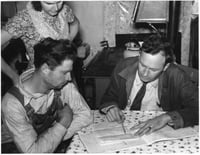 Black and white photograph of a Wilkin County farmer and his wife talk over the farm plan with the Farm Security Administration County Supervisor, ca. 1937.