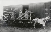 Black and white photograph of Thomas McMahon (far left), a farmer in Tara Township, loading hay onto a Great Northern Railway freight car, c.1910.