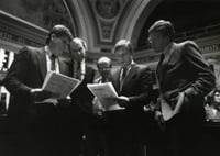 Black and white photograph of Ron Dicklich, William Luther, Allan Spear, Roger Moe, and Duane Benson reading a bill on the floor of the Minnesota Senate, 1988.