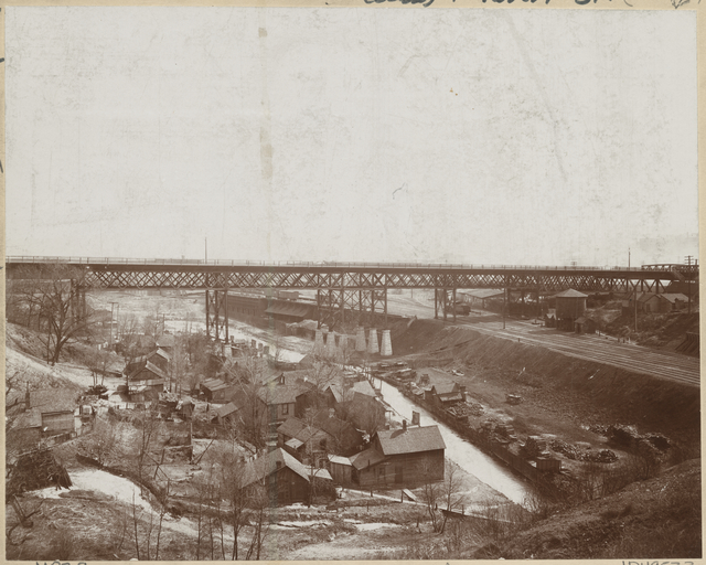 Sepia photograph of Swede Hollow with the Sixth Street Bridge in the background, ca. 1900