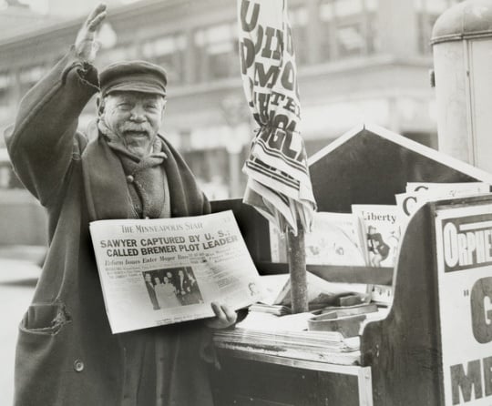 Black and white photograph of a man selling a newspaper with headline related to Bremer kidnapping, 1935.