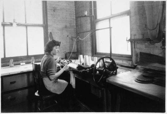 Black and white photograph of an employee knitting a sock to cover an amputated limb, Winkley Artificial Limb Company, Minneapolis, 1937.