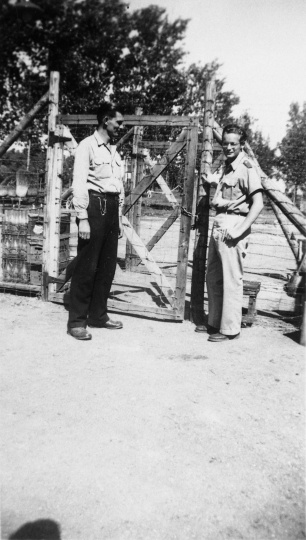Black and white photograph of Harvey Fleshner with a Peterson farm employee outside the gates of the German prisoner of war camp, ca. 1943–1945.  Used with the permission of the Historical and Cultural Society of Clay County.