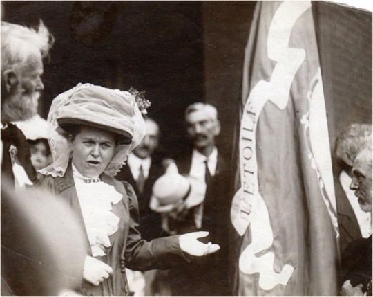 Black and white photograph of Mary Mehegan Hill speaking at a St. Paul event marking the fiftieth anniversary of the First Minnesota Volunteer Infantry Regiment’s departure for Civil War duty, 1911.. Hill presented a duplicate of an old Regimental flag to the group.