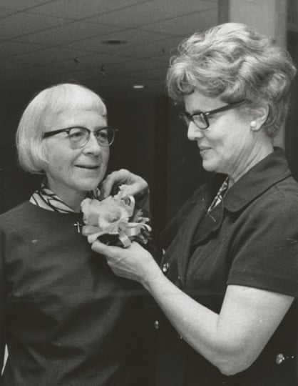 Black and white photograph of St. Catherine’s alumna Betty Hubbard (right) pinning a corsage on Alice Gustava Smith (Sister Maris Stella, left) at the College of St. Catherine in 1971. Photographed by P.J. Strasser.